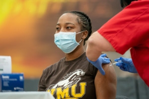 A student wearing a mask receiving the COVID-19 vaccine.