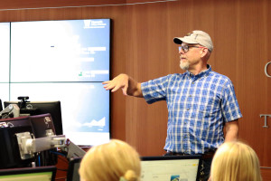 Todd Mora, wearing a blue checked shirt, teaching a class