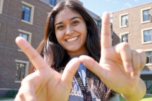 Female student makes "W" with hands. 