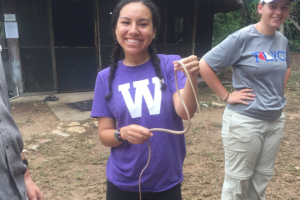 Female WMU student smiles while holding a snake in Belize.
