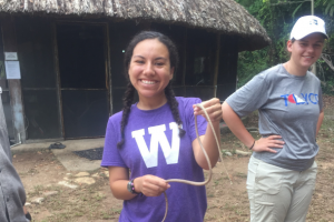 Female student in WMU shirt smiles while holding a snake in Belize.
