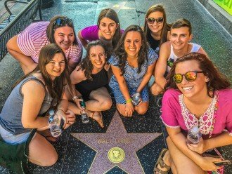 A group of honors college students crouched around Walt Disney's star on the Hollywood Walk of Fame. 