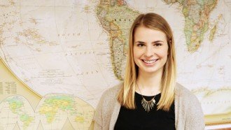 Joy Goldschmidt smiling in front of world map