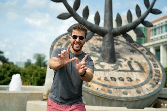Student making a "W" sign with his hands in front of WMU Seal statue