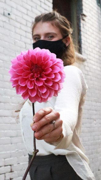 photo of Anezka wearing a face mask, holding large pink flower