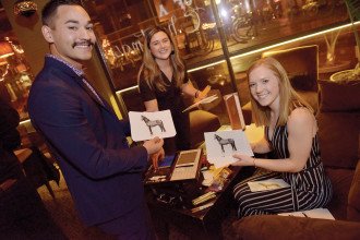 Three leadership and business strategy students smile and hold photos of Bronco artwork