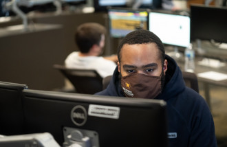 A student, masked, studies in the Greenleaf Trust Trading room.