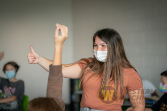 student giving thumbs up in class in a mask