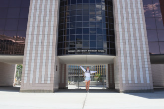 WMU student Abi Main with raised hands and and a smile on her face in front of Waldo Library.