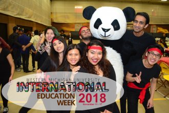 International students gathered around a large, stuffed panda bear.
