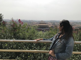 A female looking at the view of a town in China from an upper hill.