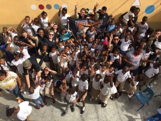 A group of local school children with WMU students, smiling at the camera.