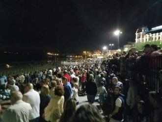 People gathering across a river in Spain at night.