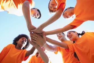 Six teenager wear orange shirts and hold each other hands.