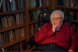 Dr. Rudolf Siebert sits in his home office surrounded by book shelves.