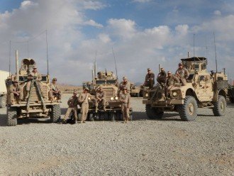 Troops in the Marine Corps stand in front of military vehicles in Afghanistan.