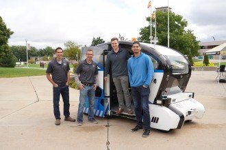 A group photo in front of the autonomous vehicle.