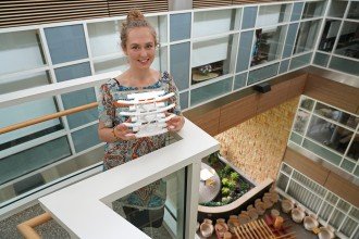 A student holds a 3D model of all four floors of the College of Health and Human Services building.
