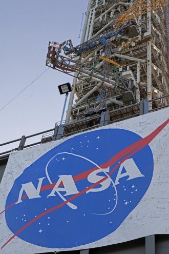 A large NASA flag is displayed on a launch pad.