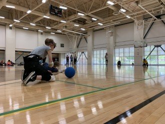 Athletes crouch in a gym to play goalball.