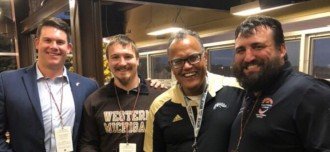 Three students pose with President Edward Montgomery in his box at the WMU football game.