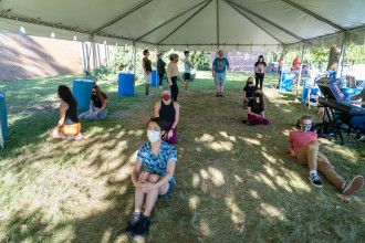 Student actors rehearse for an upcoming production outside under a tent.