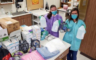 Nurses hold bottles of isopropyl alcohol and display other donated protective equipment.