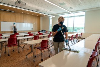 A custodian cleans a table in a classroom.