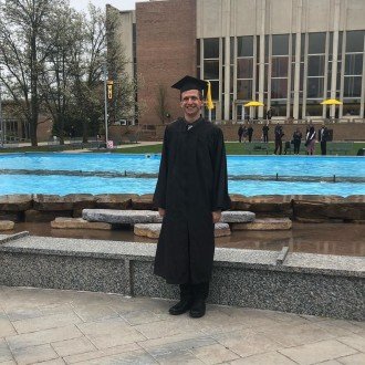 Ryan Taylor poses in his graduation regalia in front of the fountain on campus.