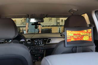 A computer monitor mounted on the back of a front passenger seat in a car.