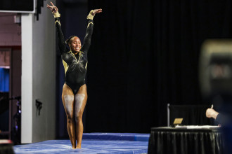 Stacie Harrison raises her arms over her head after completing a gymnastics routine.