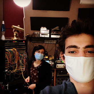 Two masked people in a sound studio.