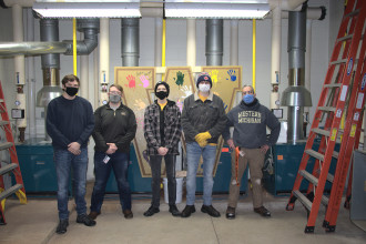 Norm Risk poses with his student employee crew in a maintenance area.