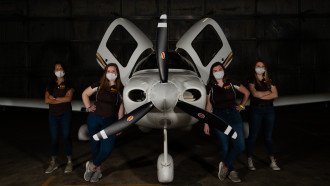 Four aviation students standing in front of a plane.