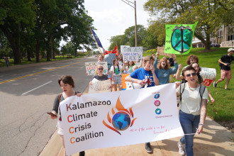 Students march across campus holding signs about climate change.