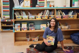 Zenia  sits on the floor in front of shelves filled with books.