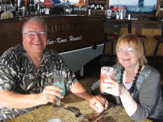 David and Joyce Lyth sit at a table of a restaurant holding cocktails.