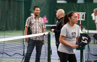 Sai Myint talks with another person on a pickleball court.