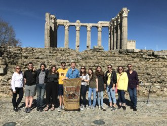 Students stand in front of the ruins of an ancient structure.