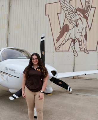 Emily Hartzell stands in front of a plane.
