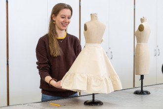 Julia LeKander places a skirt she designed on a manequin.