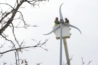 Technicians secure the blades on a wind turbine.