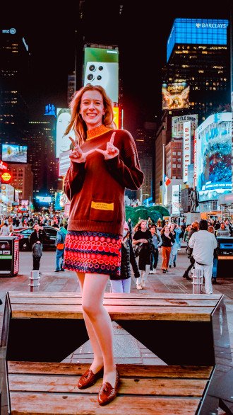 LeKander Poses for a photo flashing the Western "W" with her hands in the middle of Times Square.
