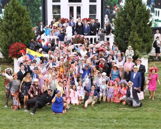 A large crowd of people pose together in the winner's circle at the Kentucky Derby.