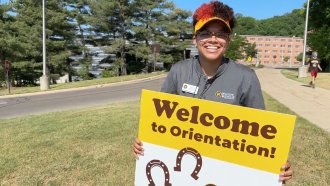 Cass Davis holds a sign that reads, "Welcome to Orientation!"