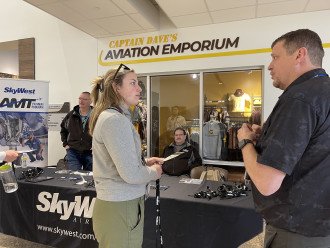 A student talks with a SkyWest representative in front of a promotional table.