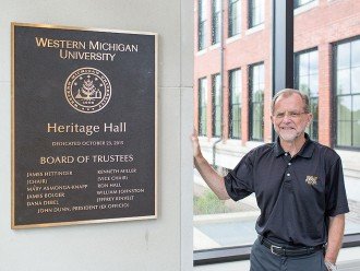 Photo of WMU President John M. Dunn with a dedication plaque for Heritage Hall.