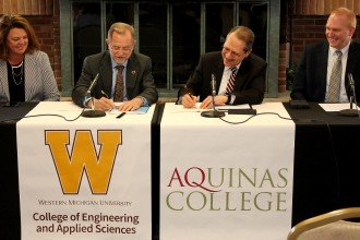 Photo of the WMU and Aquinas College's presidents signing an agreement between the two schools.