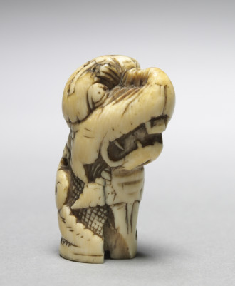 A twelfth-century ivory carving of a dragon's head with teeth bared.