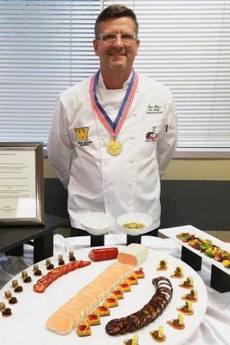 Photo of Chef Tom Giles standing in front of a platter of his award-winning food.